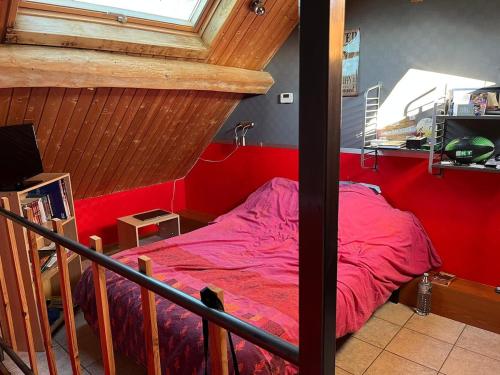 a bedroom with a bed with a red wall at Maison Le Mans in Teloché