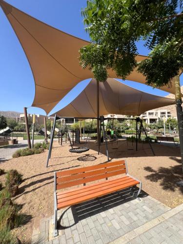 un banco de madera sentado bajo una sombrilla grande en 2 Bedrooms apartment 120M2 Muscat Bay 2 Bathrooms 2 Balconies Luxury and Landscaping, en Mascate