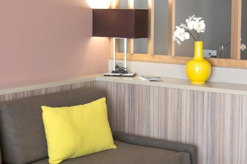 a yellow pillow on a chair in a room at Best Western Plus Ajaccio Amirauté in Ajaccio