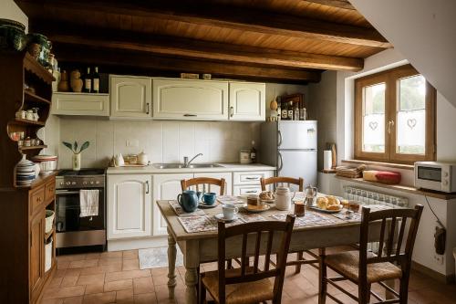 een keuken met witte kasten en een tafel met stoelen bij Villa Nasca - Paesaggi e Piscina privata in Castelraimondo