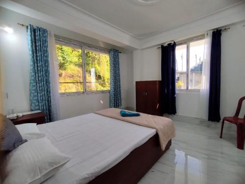 a bedroom with a large bed and two windows at Marmen Homestay in Kalimpong