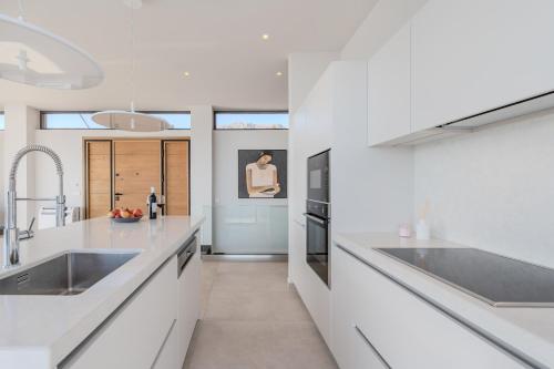 una cocina con encimeras blancas y electrodomésticos de acero inoxidable en Zeus Villa, en Sellía