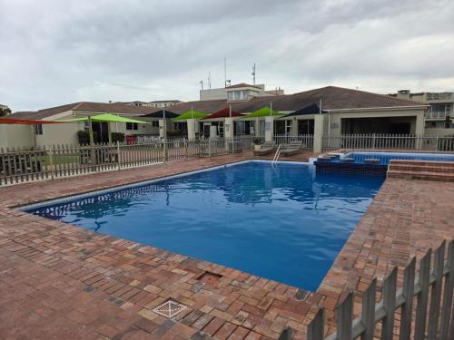 a swimming pool with blue water in front of a house at Unit 8 Hermanus Beach Club in Hermanus