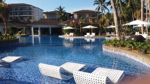 a swimming pool with chairs and umbrellas at a resort at Movenpick Resort & Spa Boracay in Boracay
