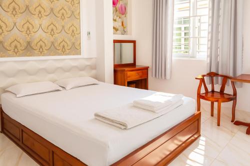 a bedroom with a bed with white sheets and a chair at Sao Mai Hotel Can Tho in Can Tho