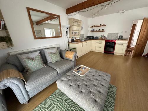 a living room with a couch and a kitchen at Cosy one bed cottage in Anglesey in Llanddyfnan