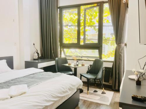 een slaapkamer met een bed, een bureau en een raam bij Levi Living in Da Nang
