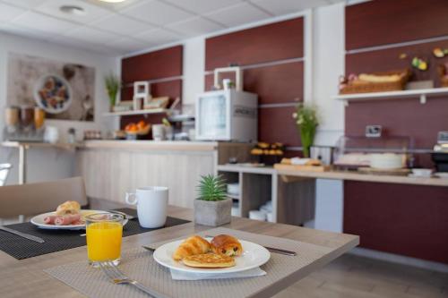 a table with two plates of pastries and orange juice at Comfort Aparthotel Cannes Mandelieu in Mandelieu-la-Napoule