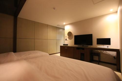 a bedroom with a bed and a desk with a television at The Ace Hotel in Seoul