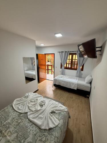 a bedroom with two beds and a tv on the wall at Suítes Refúgio in Abraão