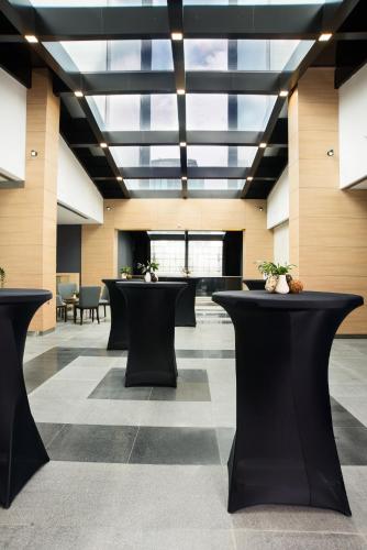 a lobby with black tables and a glass ceiling at Premier Sofia Airport Hotel in Sofia