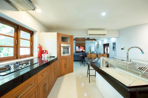 a large kitchen with wooden cabinets and black counter tops at Pool Villas by Honey - Luxury Family Resort-8 km from Beach & Nightlife in Nong Prue