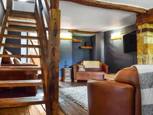 a living room with a staircase and a couch at Juniper Cottage in Hook Norton