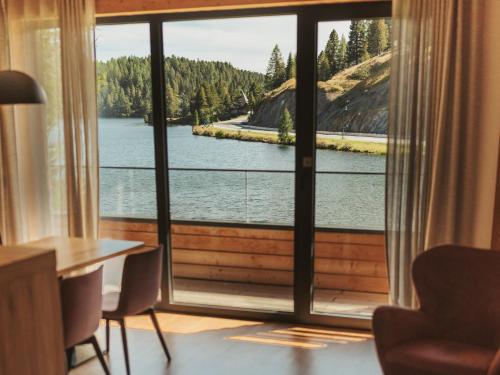 a room with a large window with a view of a lake at Alpin Peaks in Turracher Hohe