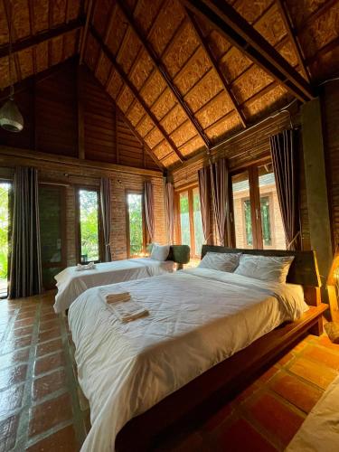 a bedroom with two beds in a room with windows at Kung Nok Tha Resort Nakhon Si Thammarat in Nakhon Si Thammarat
