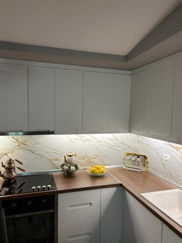 戈里察villa dervishaj的厨房配有白色橱柜,柜台上放着一碗水果