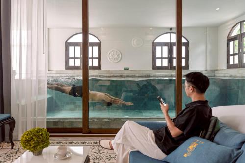 a man sitting on a couch in front of a swimming pool at Siri Villa Chiang Mai in Chiang Mai