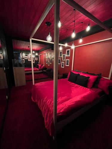 a red bedroom with a large bed with red sheets at Romantic house with hot tub in Poelkapelle