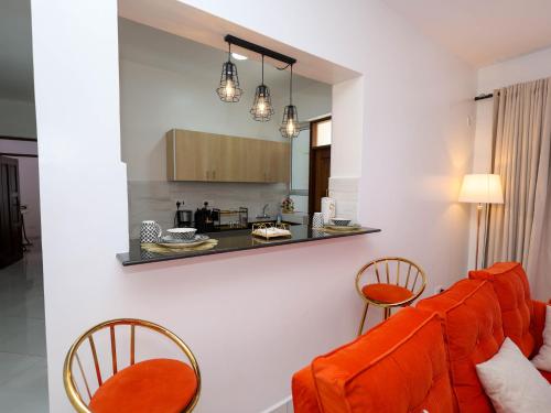 a living room with an orange couch and two chairs at Cosy 2 Bedroom at Ganjoni near the landmark site at Pembe za Ndovu - Elephant Task in Mombasa