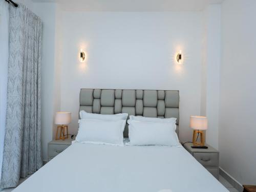 a bedroom with a large white bed with two lamps at Cosy 2 Bedroom at Ganjoni near the landmark site at Pembe za Ndovu - Elephant Task in Mombasa