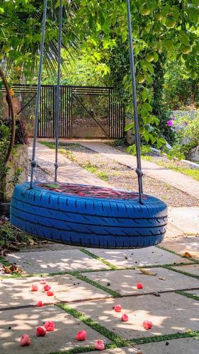 a tire swing in a park with flowers on the ground at Nostalgia Homestay in Vythiri
