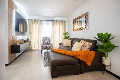 a living room with a brown couch and a tv at Deplatinum Luxury Apartment-A Home away with love in Sandton