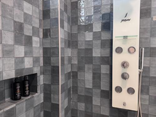 a shower with gray tiled walls and black bottles at Turiya Retreat in Auroville