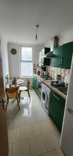 a kitchen with green cabinets and a washing machine at Home on Piccadilly Line in London