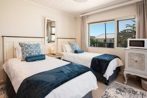 two beds in a room with a window at Stylish OceanBreeze 50 Central Mossel Bay in Mossel Bay