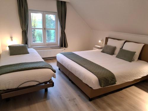 a bedroom with two beds and a window at De Horizon in de Westhoek in Poperinge
