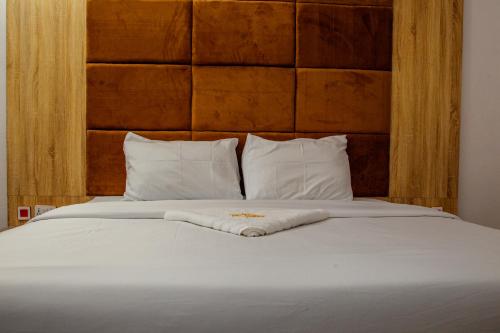 MeranにあるDel Migos Hotel & Suitesの白いベッド(木製のヘッドボード、白い枕付)