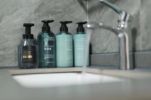 un gruppo di tre bottiglie di shampoo appoggiate sul lavandino del bagno di Dali Linghaoyun Homestay a Dali