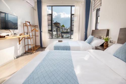 una camera d'albergo con due letti e una grande finestra di Dali Linghaoyun Homestay a Dali