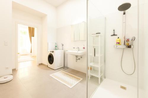 a white bathroom with a shower and a washing machine at Stilvolles Altbau Apartment - 2 Min zur U-Bahn, Nähe Donaukanal in Vienna