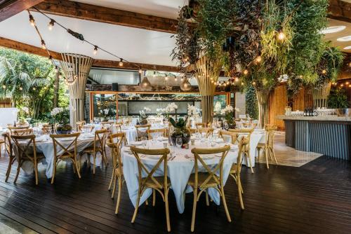 a dining room with white tables and chairs at Kauri Springs Lodge still the same beautiful place but so so much better in Waiheke Island