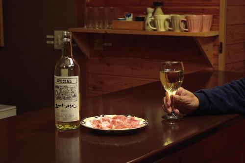 a person holding a glass of wine and a plate of food at Sasamori House in Azumino
