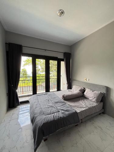 a bedroom with a bed and a large window at Villa Andira Hidden Paseban in Pondok Cipaseban