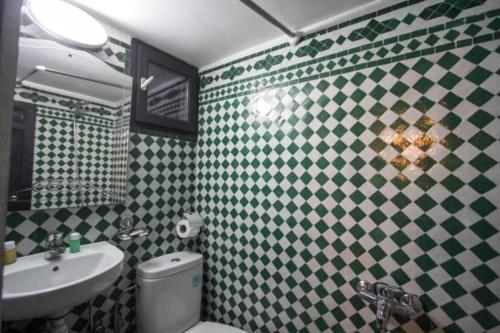 a bathroom with green and white tiled walls and a sink at ROOM iN FES MEDINA in Fès