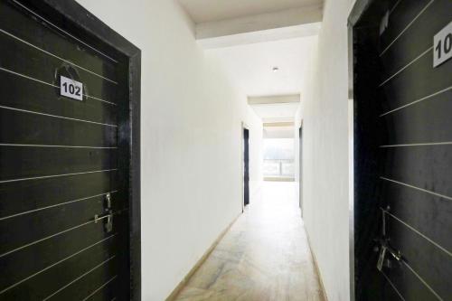 - un couloir avec des portes noires, des murs blancs et du parquet dans l'établissement Hotel O Raj Mahal, à Jabalpur