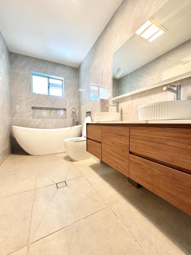 a bathroom with a tub and a toilet and a sink at Master room with Ensuite Near Train Station Airport in Revesby