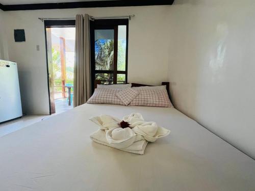 a white bed with a flower on top of it at Kiera Homestay in General Luna