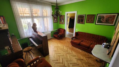 a living room with green walls and a couch and a piano at Folks HOME in Novi Sad