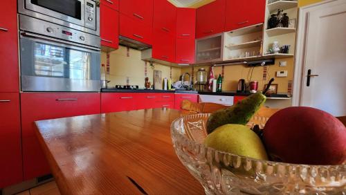 a kitchen with red cabinets and a bowl of fruit on a table at Folks HOME in Novi Sad