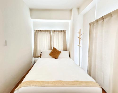 a small bedroom with a white bed with a window at mori house西が丘 in Tokyo