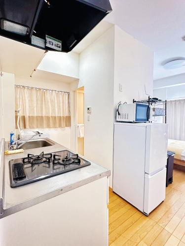 a kitchen with a stove and a white refrigerator at mori house西が丘 in Tokyo