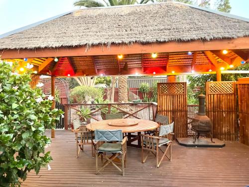 SmithfieldにあるGuest suite in Elizabeth Northの茅葺き屋根の下にテーブルと椅子が置かれた木製のデッキ