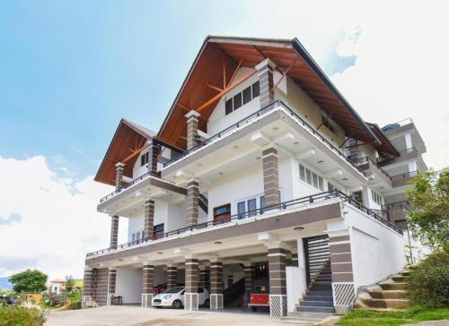 een groot wit huis met een dak bij Queens Lake Cabin in Nuwara Eliya
