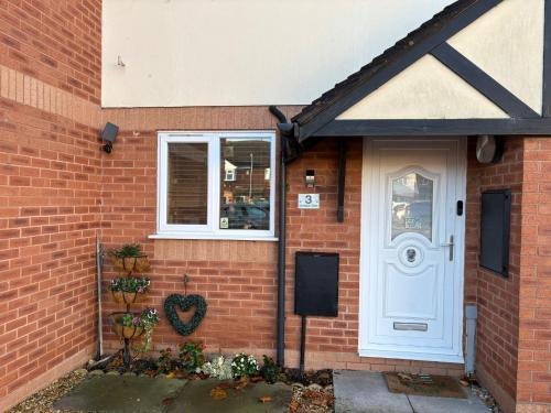 ein Backsteinhaus mit einer weißen Tür und einem Fenster in der Unterkunft Gorgeous Sandpiper Mews in Worcester