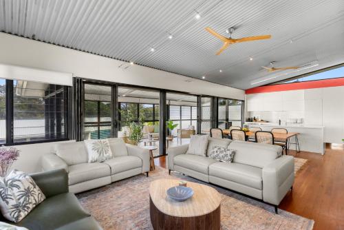 an open living room with couches and a table at Stunning Ocean-View Home, Walk to Village & Beach in Sawtell