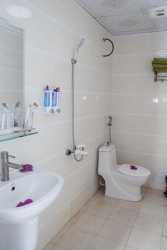 a white bathroom with a toilet and a sink at Grand Ireland hotel in Cat Ba